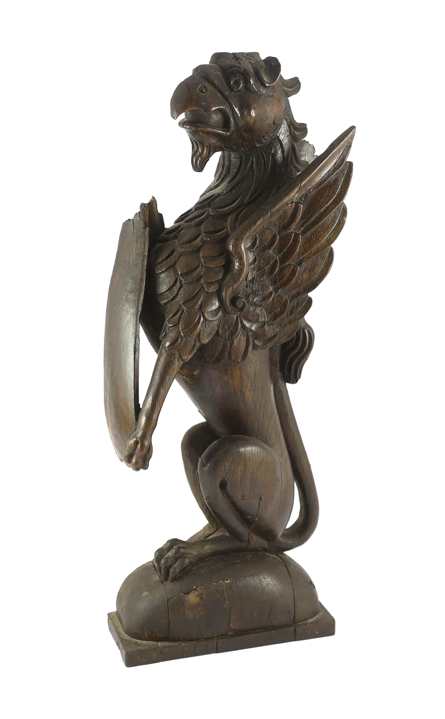 A 16th century Dutch carved oak model of a griffin rampant holding a shield